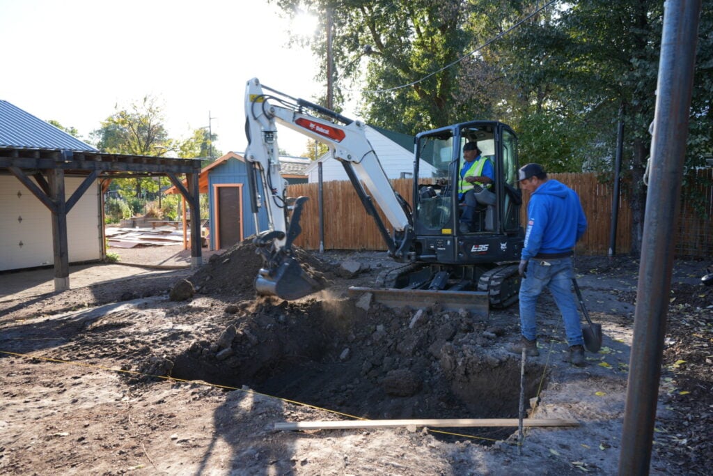 Mini excavator digging at residential construction site.