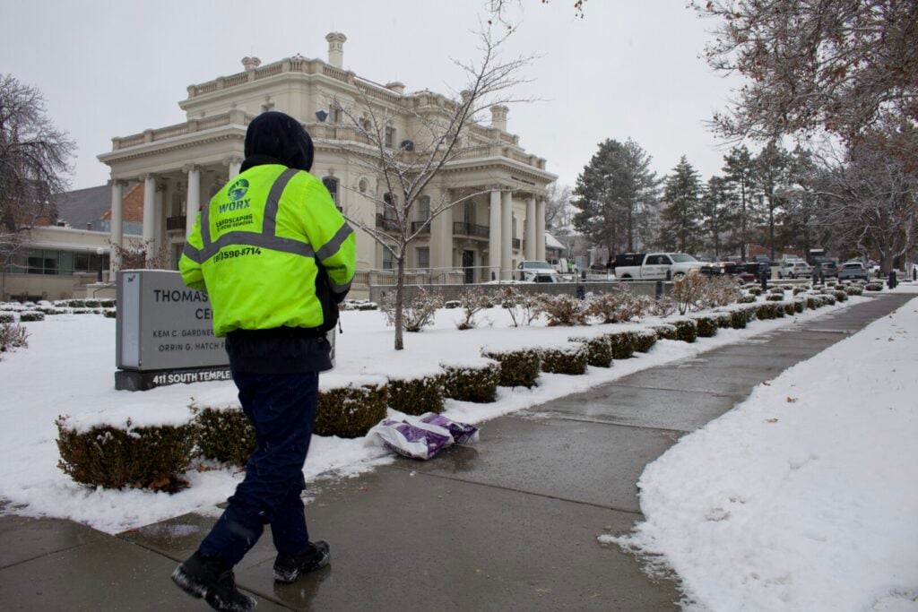 Worker in snow clearing pathway near building