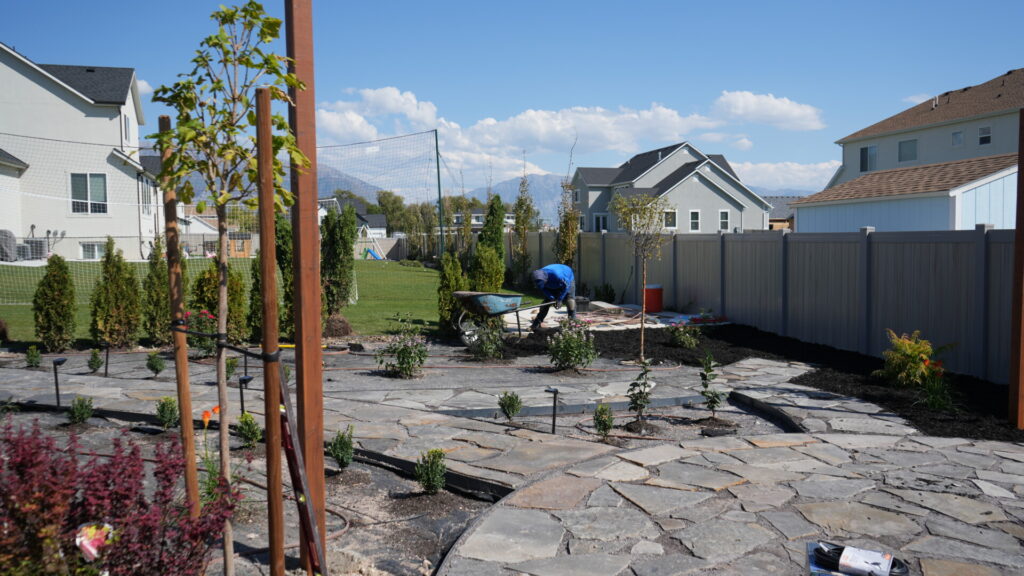 Backyard landscaping with stone path and worker