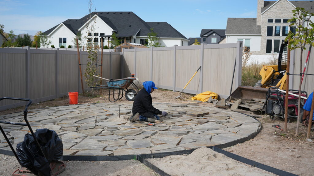 Worker installing stone patio in backyard