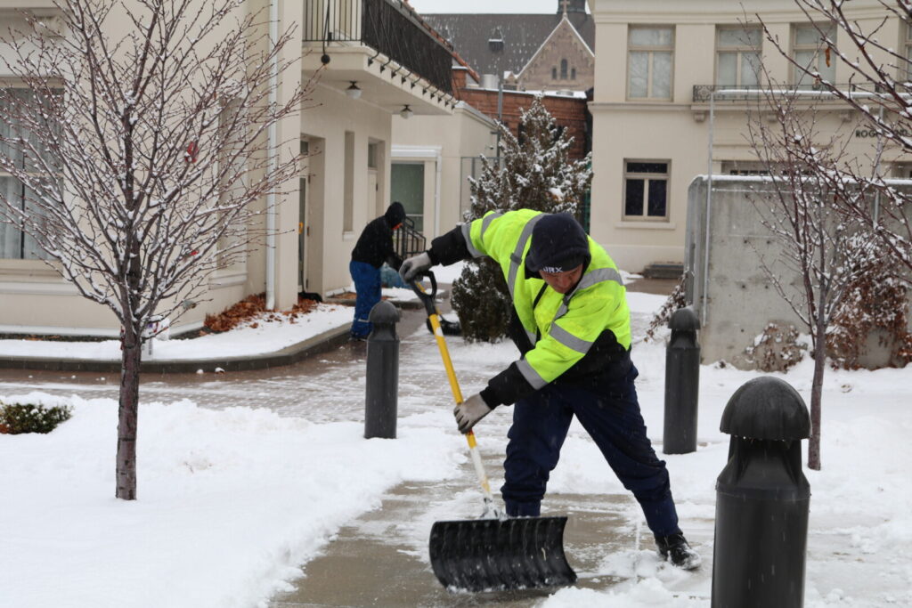 Workers shoveling snow from a sidewalk