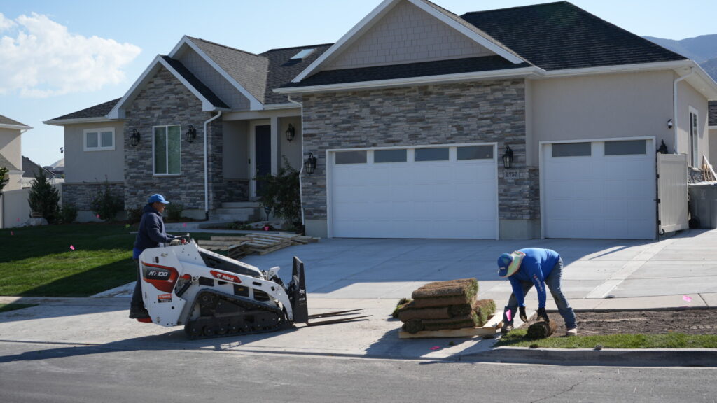 Workers laying sod outside residential house