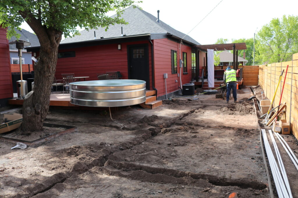 Backyard renovation with worker and stock tank pool.