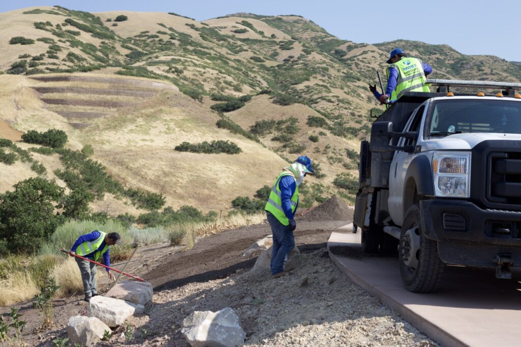 Workers in safety vests on hillside road construction.