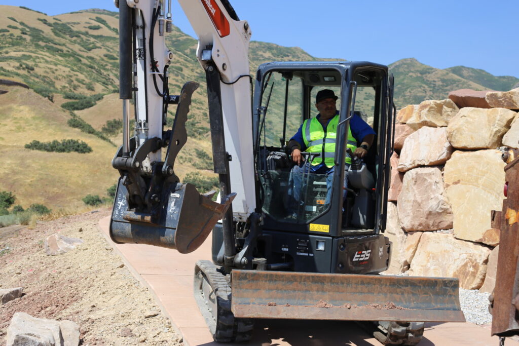 Worker operating excavator on rocky hillside