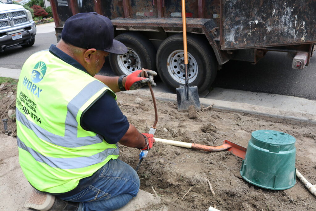 Worker fixing underground pipes on a construction site.