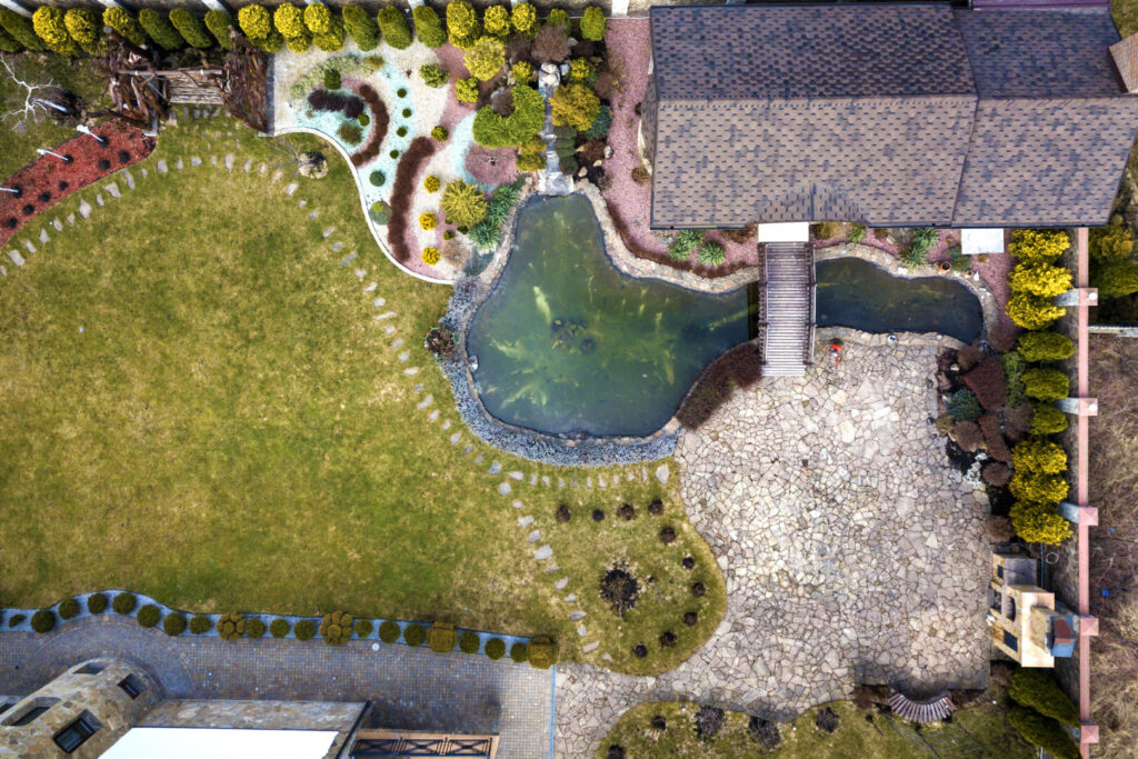 Aerial view of landscaped garden with pond and bridge.