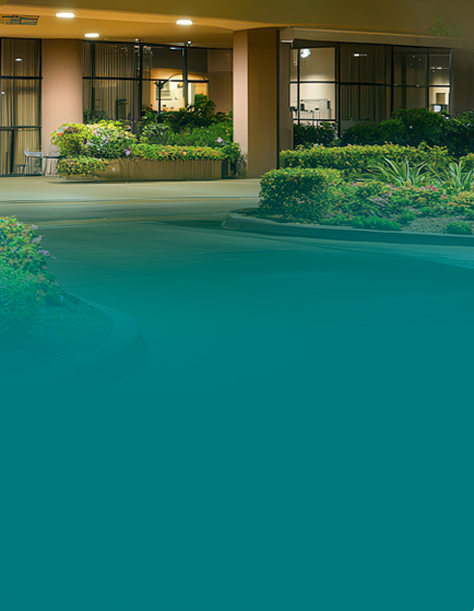 Nighttime view of building entrance with landscaping.