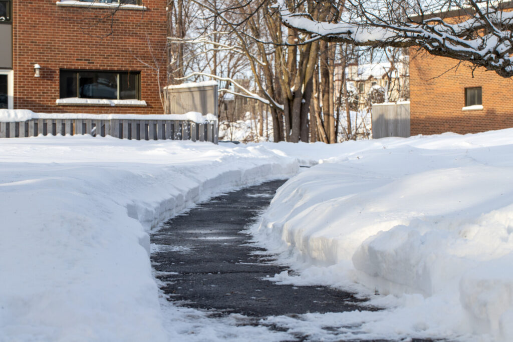 Pathway through snow near brick building